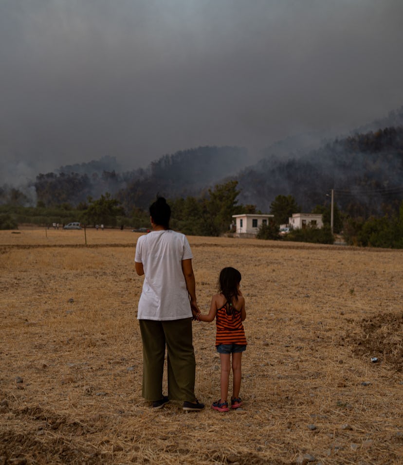 TOPSHOT - A woman and child stand in a field as they watch wildfires as they burn in Koycegiz distri...