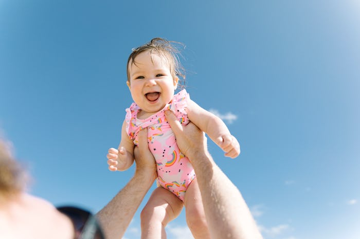 smiling baby being held in the sky deserves a baby name that means light