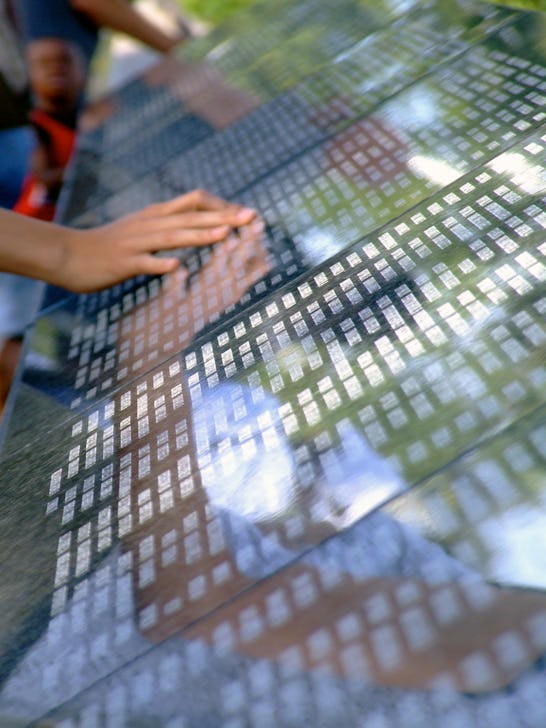 Memorial wall  overlooking New York City.  A hand touches the names of victims of September 11.  See...