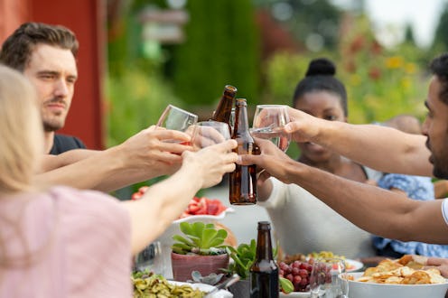 A multiethnic group of young friends enjoy good food and conversation together on a terrace outside ...