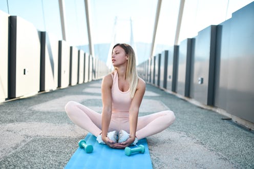 Stretching And Meditation Time For Beautiful Blond Female Athlete On Bridge Outside