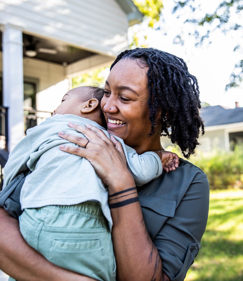Mother holding toddler in front of new home