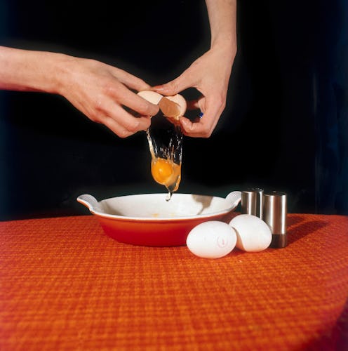A woman cracks an egg into a dish. Experts explain how to become an egg donor.