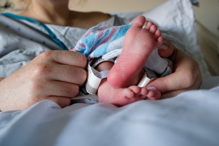 A newborn baby rests in their parents' arms shortly after birth.