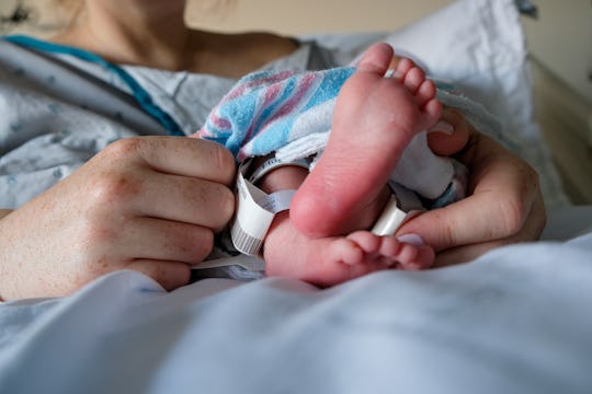 A newborn baby rests in their parents' arms shortly after birth. 