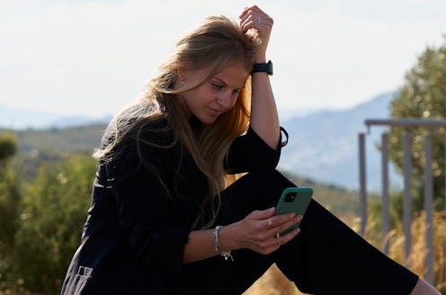 Side view of blonde sitting on the floor looking her mobile phone