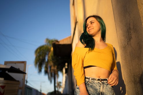 Portrait of beautiful young woman with green hair in the street with sunligth.
