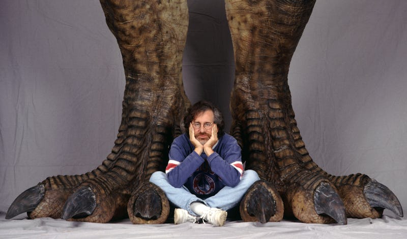American director Steven Spielberg poses between a pair of giant dinosaur feet in a publicity still ...