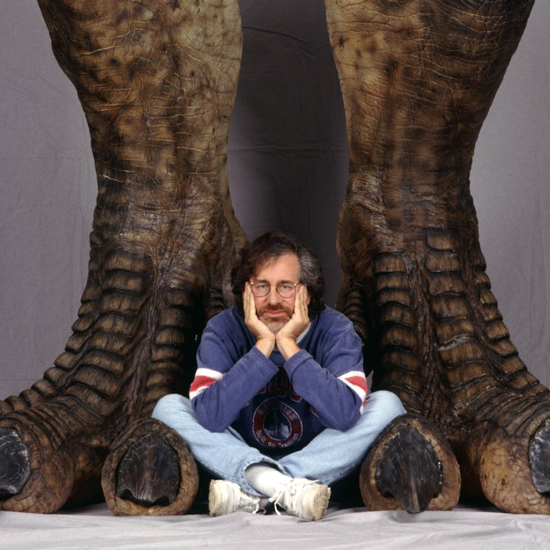 American director Steven Spielberg poses between a pair of giant dinosaur feet in a publicity still ...