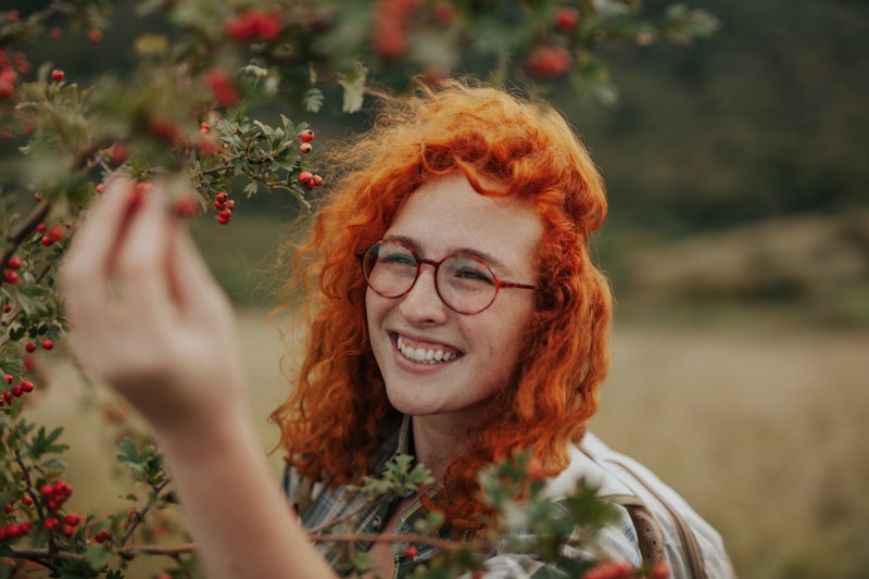 Spontaneous portrait of a cute and cheerful young adult woman, a ginger with eyeglasses on, explorin...