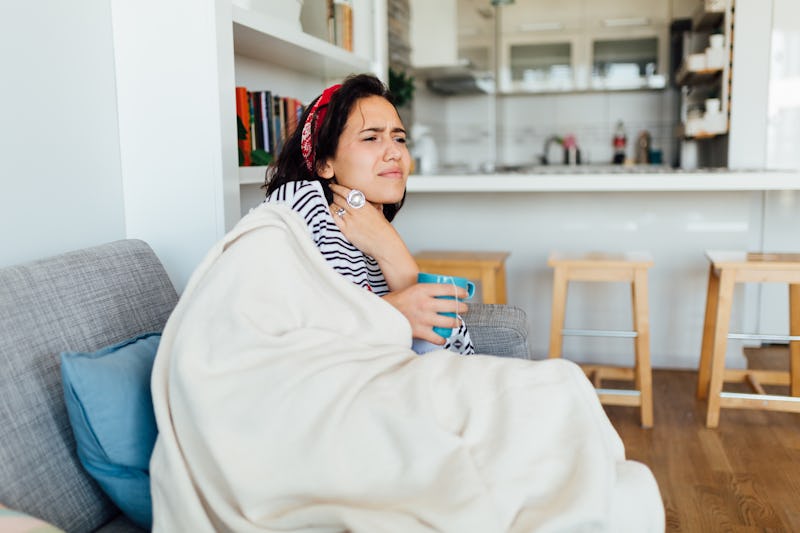 Young Caucasian woman staying at home due to her being sick, staying in quarantine and pushing throu...