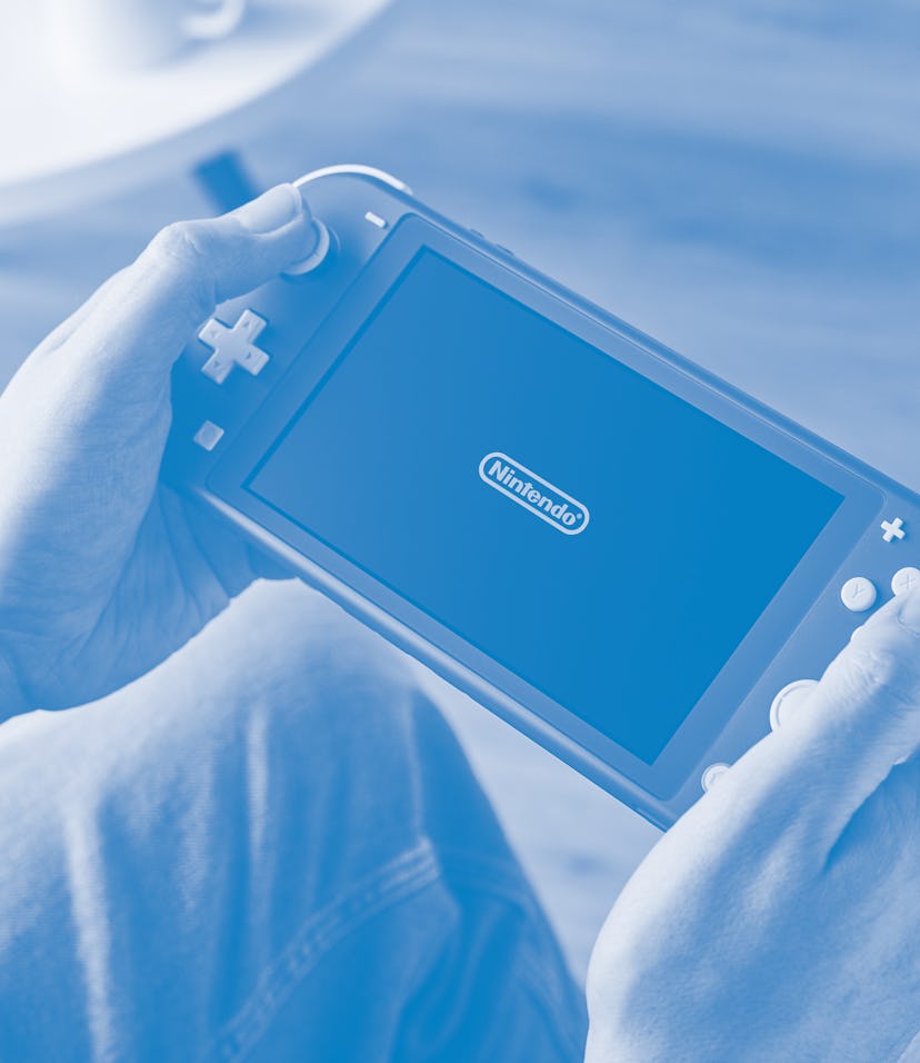 Detail of a person holding and playing a 2019 Nintendo Switch Lite handheld video games console with...