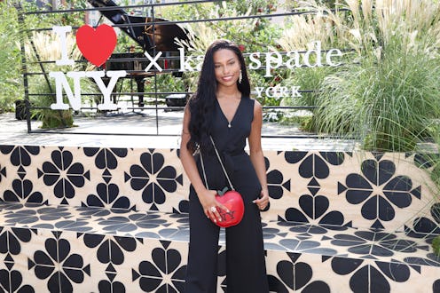 Savannah Smith wearing a black dress with a red apple shaped handbag