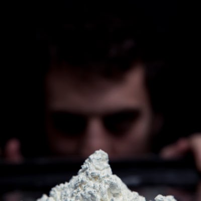 A guy looking at a heap of cocaine from a distance