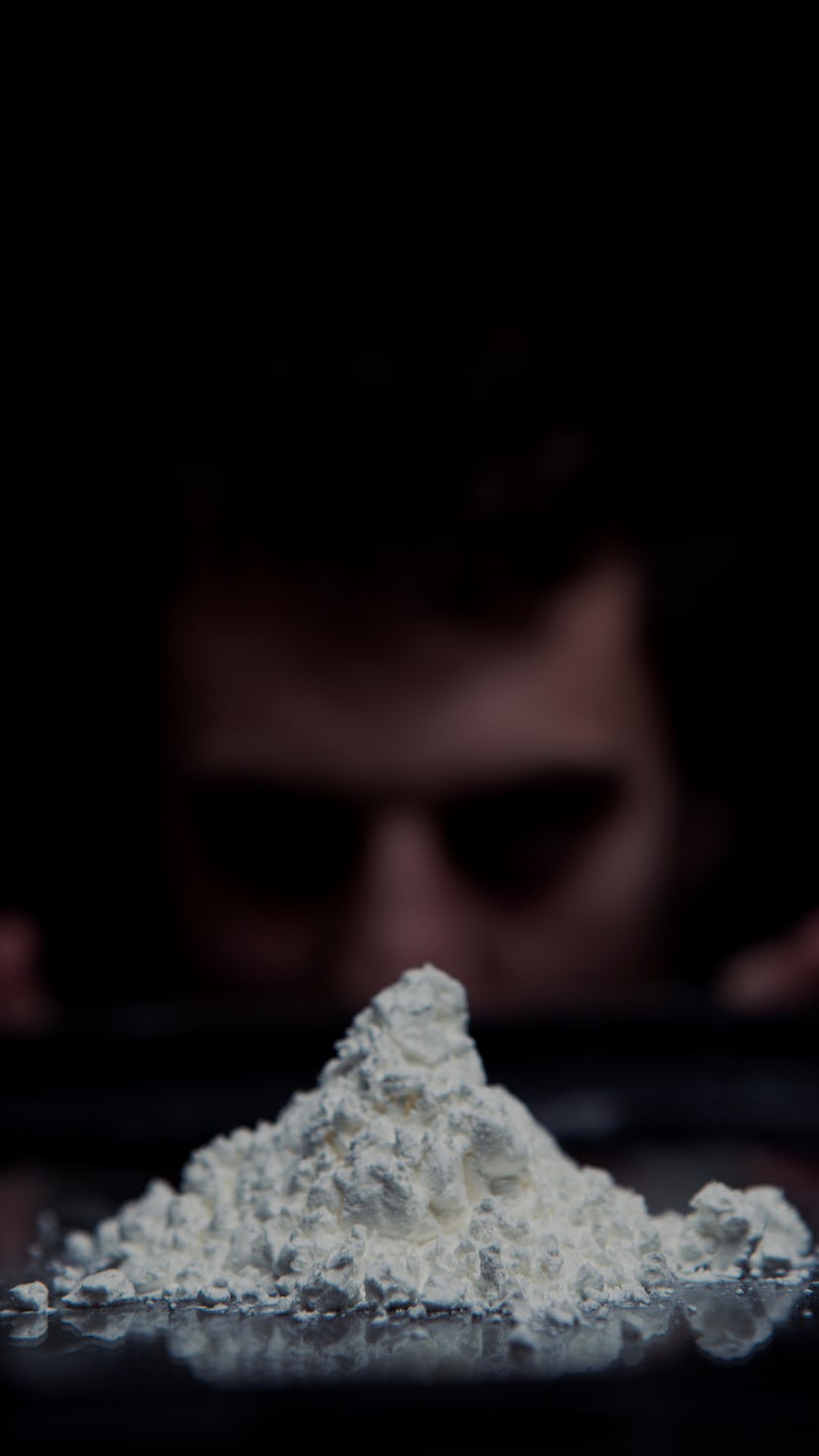 A guy looking at a heap of cocaine from a distance
