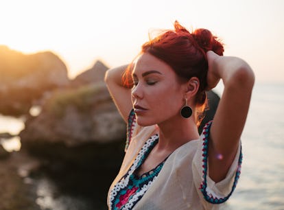 Young woman with long red hair enjoys beautiful sunset during the October 2021 new moon in Libra, wh...