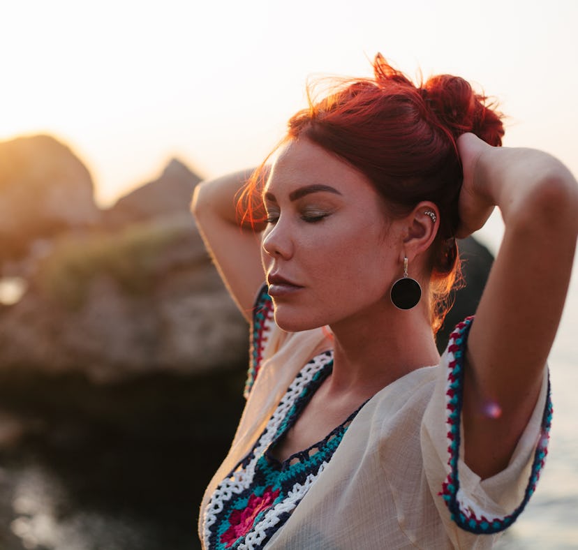 Young woman with long red hair enjoys beautiful sunset during the October 2021 new moon in Libra, wh...