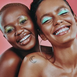 Shot of two beautiful young women posing together against a pink background