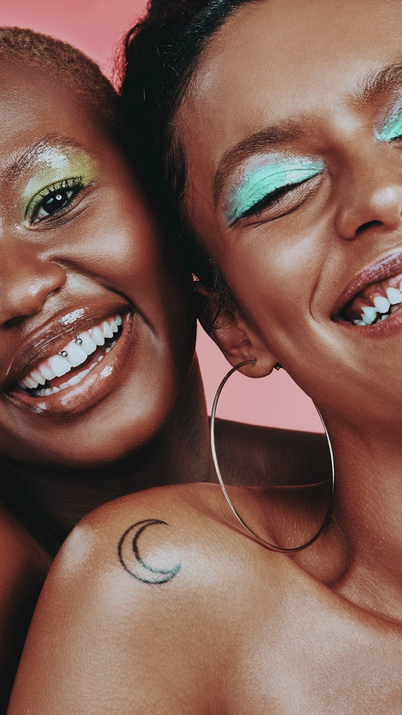 Shot of two beautiful young women posing together against a pink background