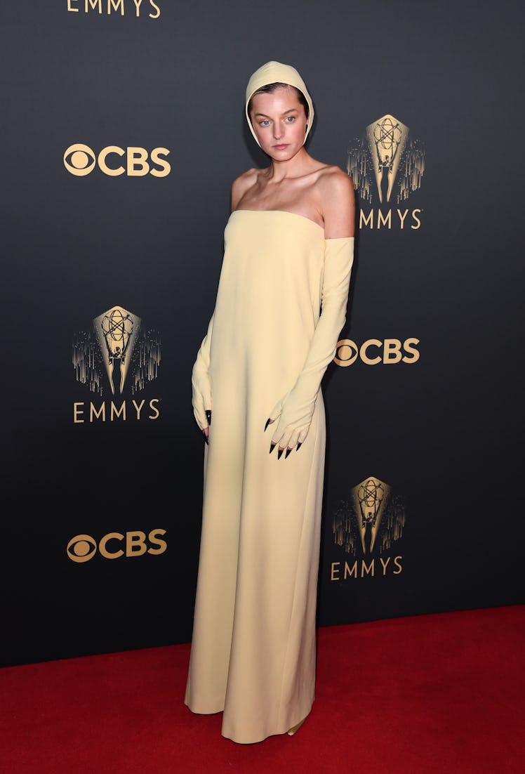 Emma Corrin in a beige dress, gloves and head piece at the Emmys Red Carpet 2021