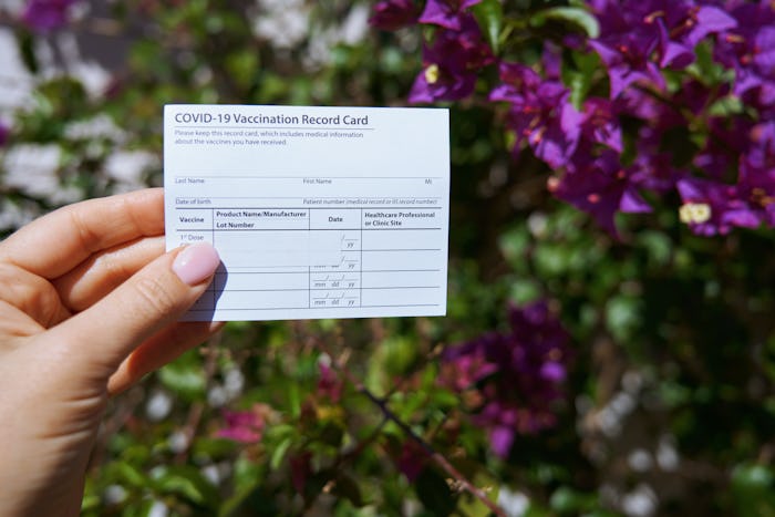 Woman holding covid-19 vaccination record card outdoors