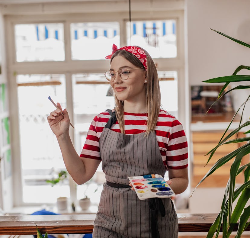 A young woman paints a DIY sorority paddle from an idea on TikTok.