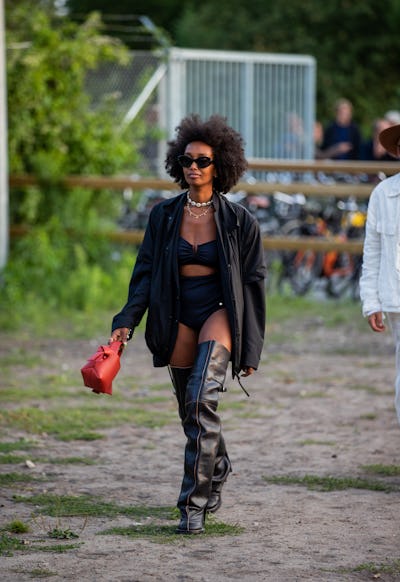 A young fashionable Black woman demonstrates how to wear over-the-knee boots at an event