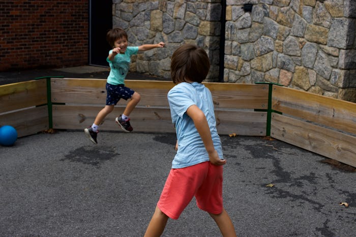 Action shot of two young boys playing with a ball in a gaga pit in the schoolyard.