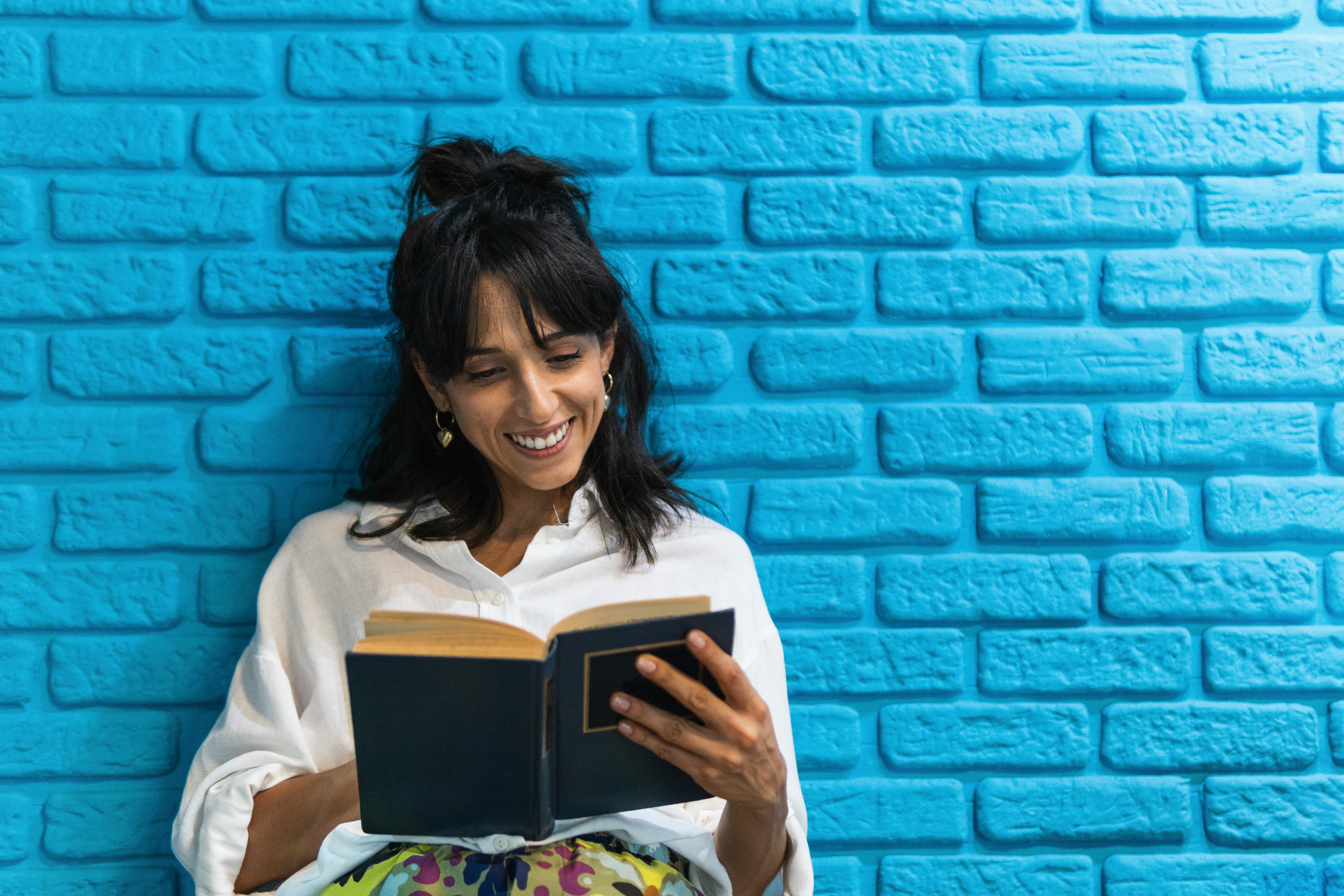 A reader in a crisp white shirt smiles at an open book.