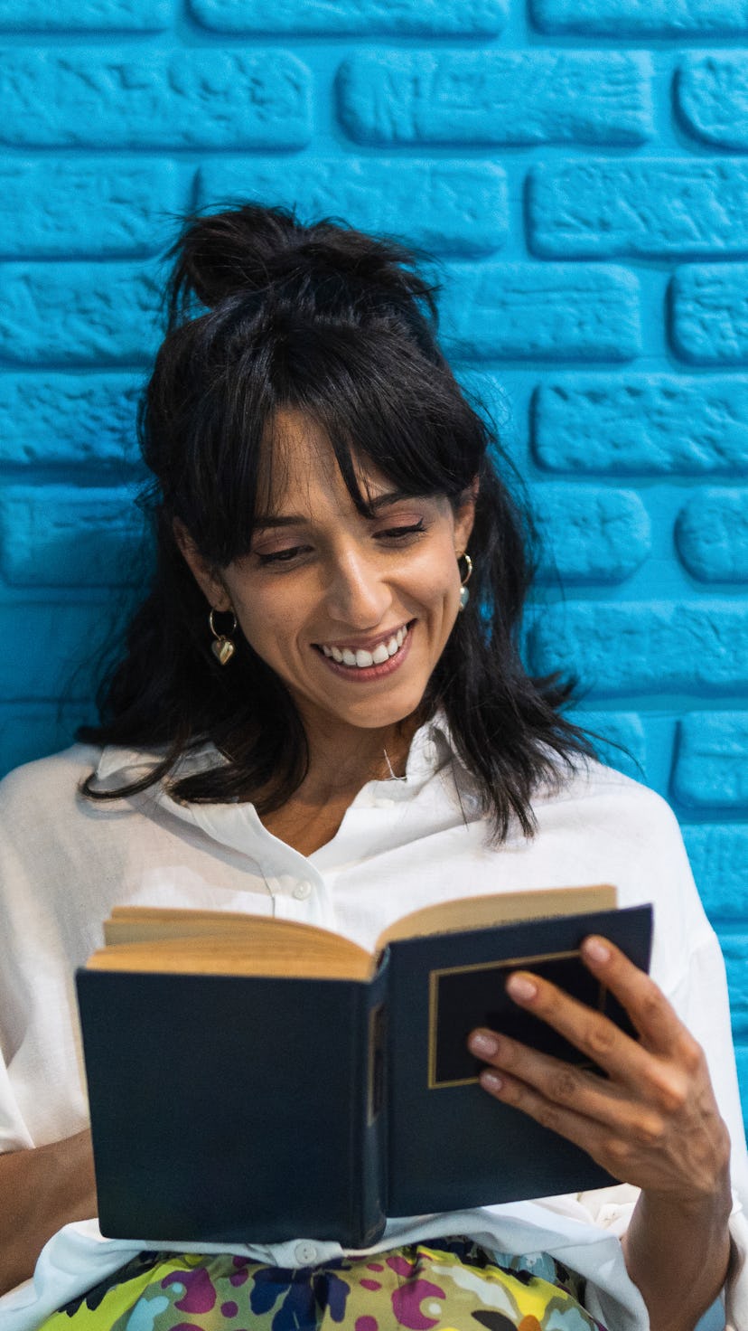 A reader in a crisp white shirt smiles at an open book.