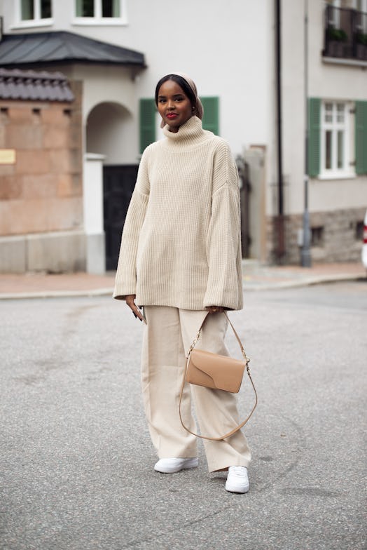 A monochromatic sweater outfit in beige, with sneakers and a bag.