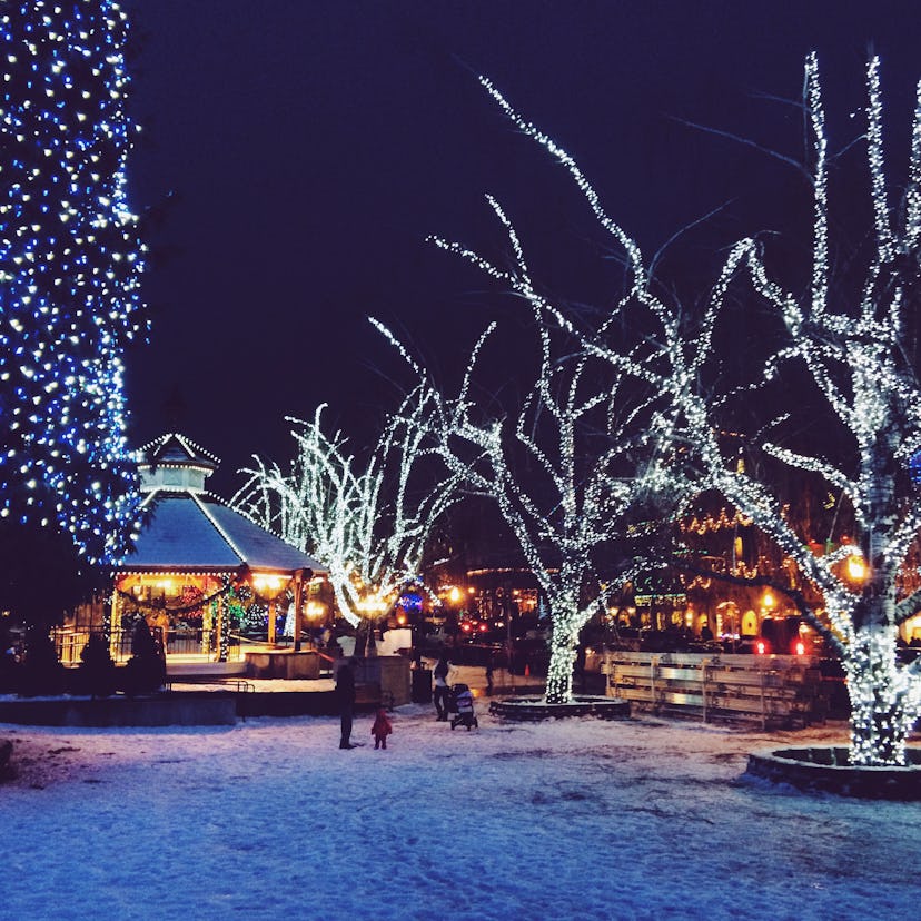The town of Leavenworth, Washington sits at twilight on a snowy, winter night lit by Christmas light...