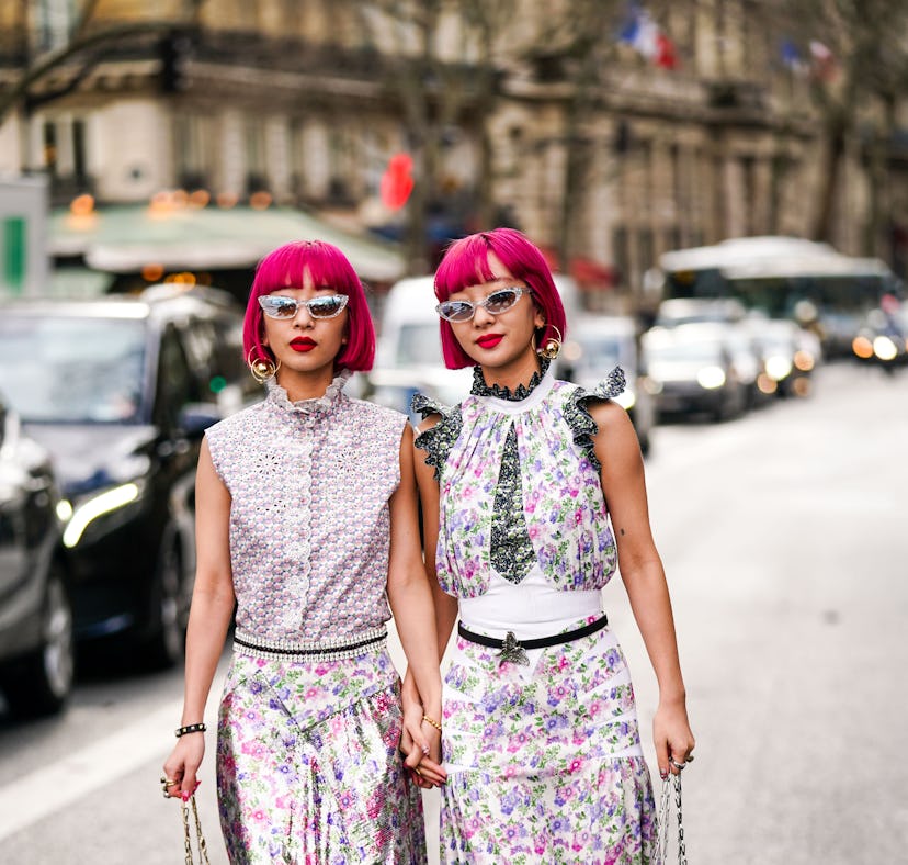 Fashion twins Ami and Aya Suzuki have hot pink hair and wear a floral print dresses during Paris Fas...