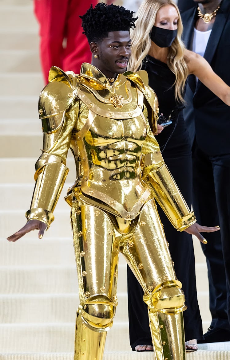 Lil Nas X attends The 2021 Met Gala while wearing gold-plated armor designed by Versace.