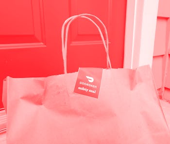 Close-up of the top of a brown paper bag, with handles and a red and white DoorDash safety seal stic...