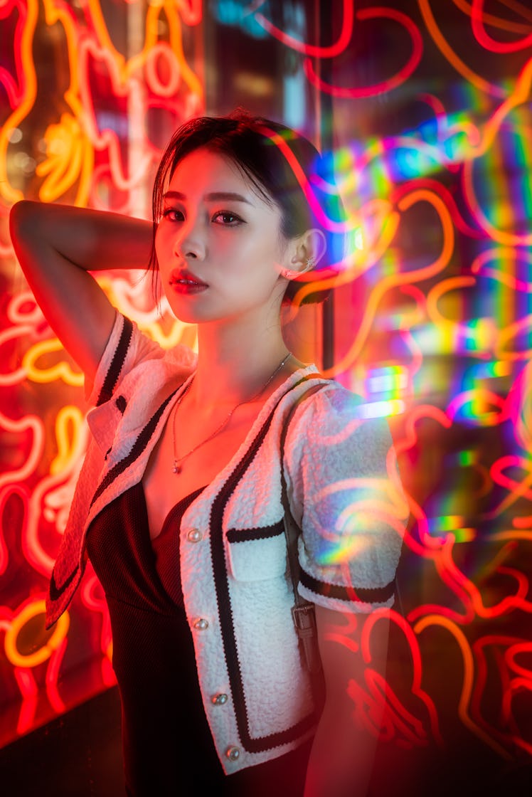 Young woman surrounded by neon lights, thinking about how Mercury retrograde fall 2021 ending will a...