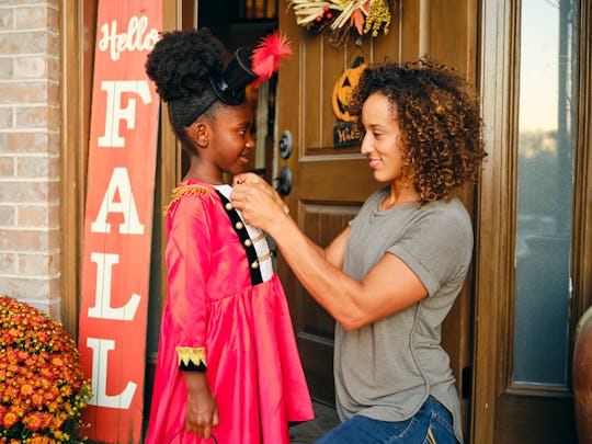 A mother prepares a child’s costume before going out trick or treating on Halloween.