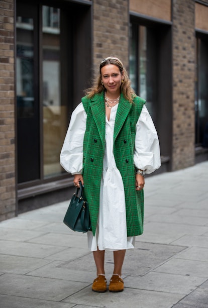 LONDON, ENGLAND - SEPTEMBER 19: A guest is seen wearing green sleeveless coat, white dress outside R...