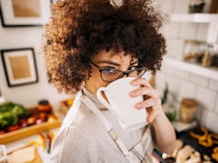 A woman in her kitchen enjoys some of TikTok's viral angel milk recipe variations from a mug.