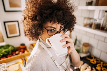 A woman in her kitchen enjoys some of TikTok's viral angel milk recipe variations from a mug.