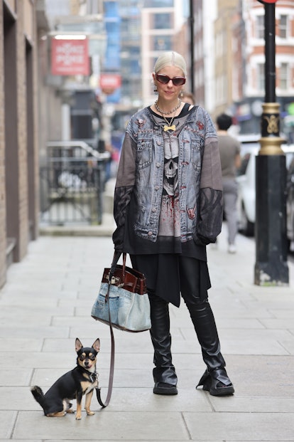 LONDON, ENGLAND - SEPTEMBER 19: Guest wearing black boots, grunge top and jacket, with dog, sunglass...