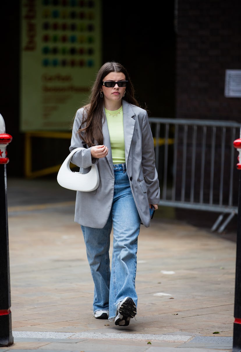 LONDON, ENGLAND - SEPTEMBER 17: A guest is seen wearing grey blazer, white bag, denim jeans outside ...