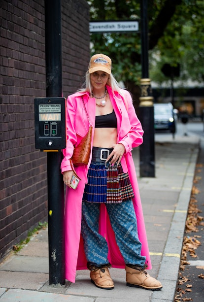 LONDON, ENGLAND - SEPTEMBER 18: A guest is seen wearing pink coat, skirt with belt, Louis Vuitton pa...