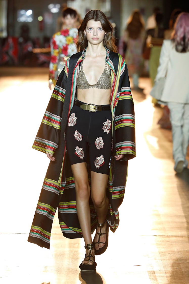 A model at the Etro fashion show at Milan Fashion Week Spring 2022 in a grey bra, black floral short...