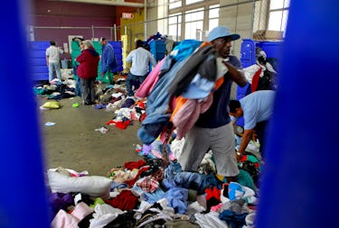 People sorting through the bins of clothing at the Goodwill As-Is store near the corner of 11th and ...