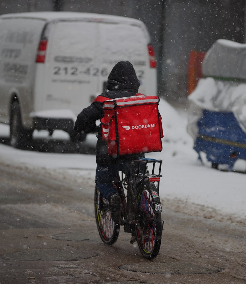 NEW YORK, USA - FEBRUARY 18: A food delivery guy with bicycle is seen as snowfall blankets the Times...