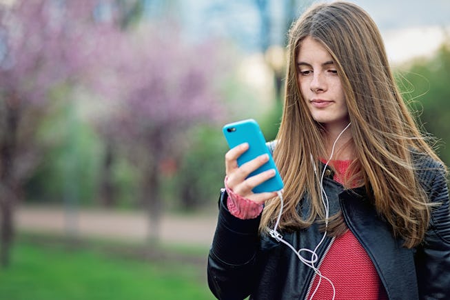 Portrait of beautiful teen girl listening to music in a park