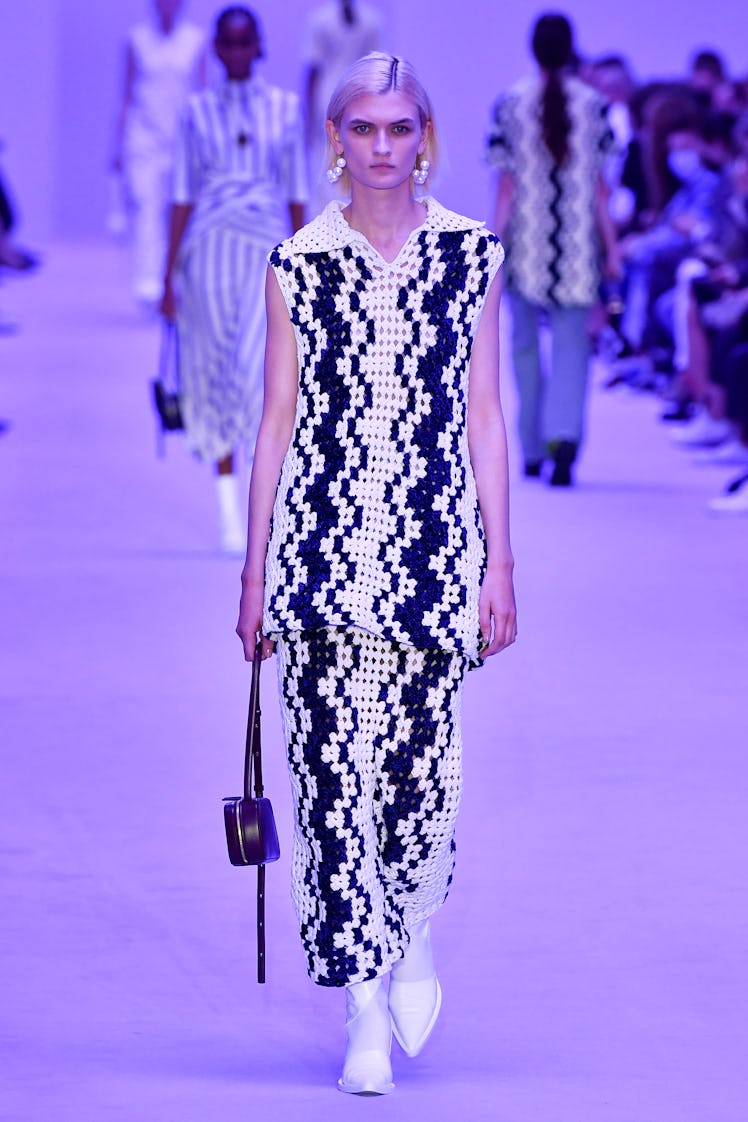 A model walking the Jil Sander show at Milan Fashion Week Spring 2022 in a blue and white embroidere...