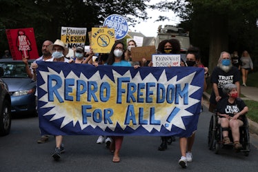 Pro-choice demonstrators march with a sign reading, "Repro Freedom For All"/