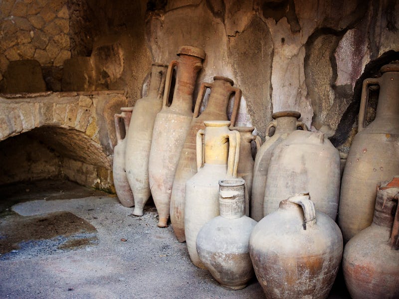 Jugs lining the walls of a "kitchen" are at the ruins of Herculaneum or Ercolano, Italy.  This Roman...